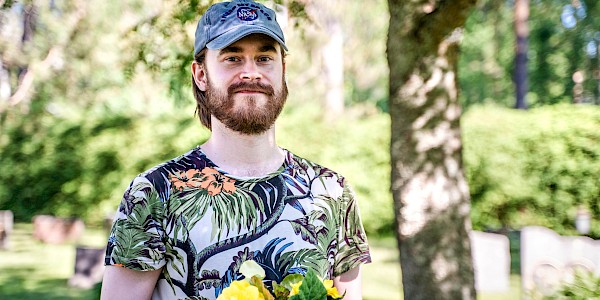 Puisto- ja puutarhatyöntekijä poseeraa seurakunnan hautausmaalla kesäisenä päivänä.